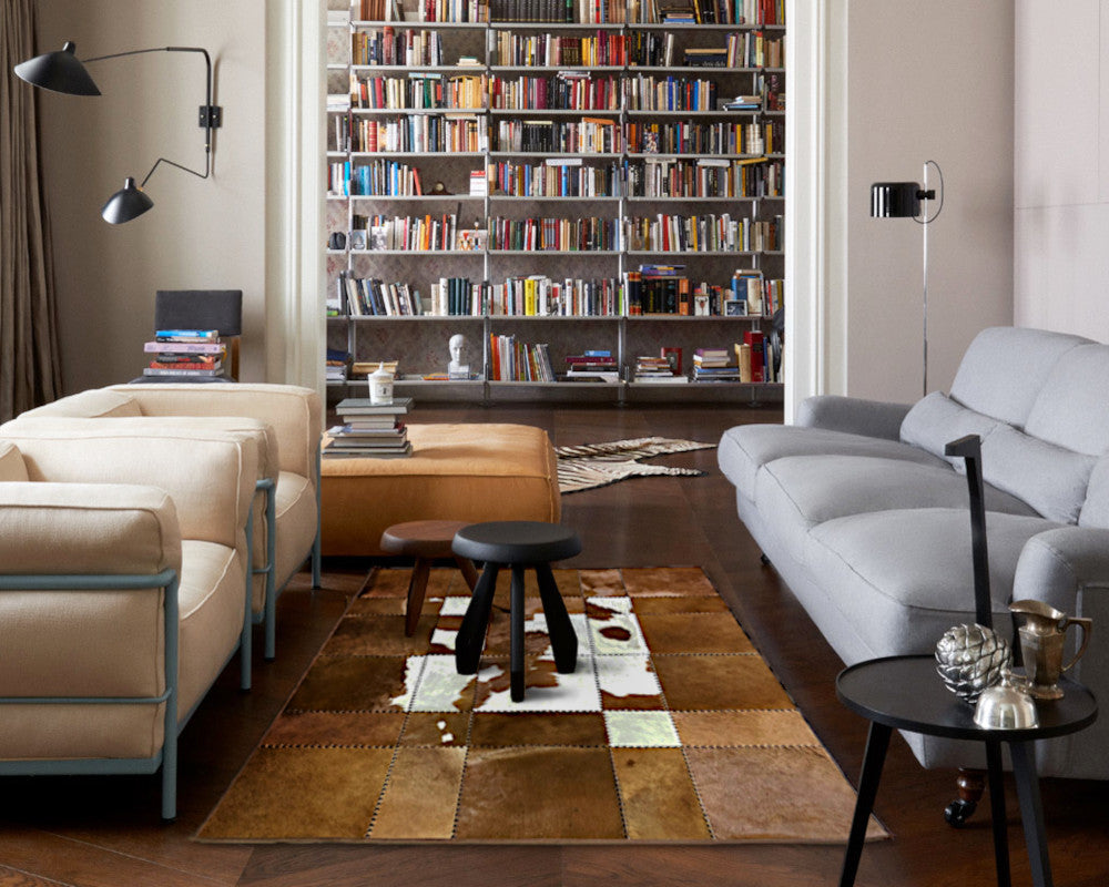 A rectangular patchwork cowhide wall art panel featuring stitched square sections in various shades of tan, brown, cream, and white, shown against a plain white background.
