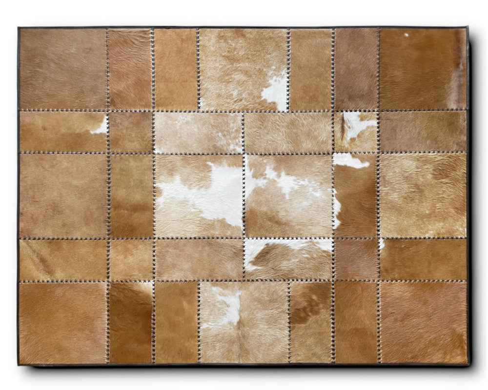A rectangular patchwork cowhide wall art panel featuring stitched square sections in various shades of tan, brown, cream, and white, shown against a plain white background.
