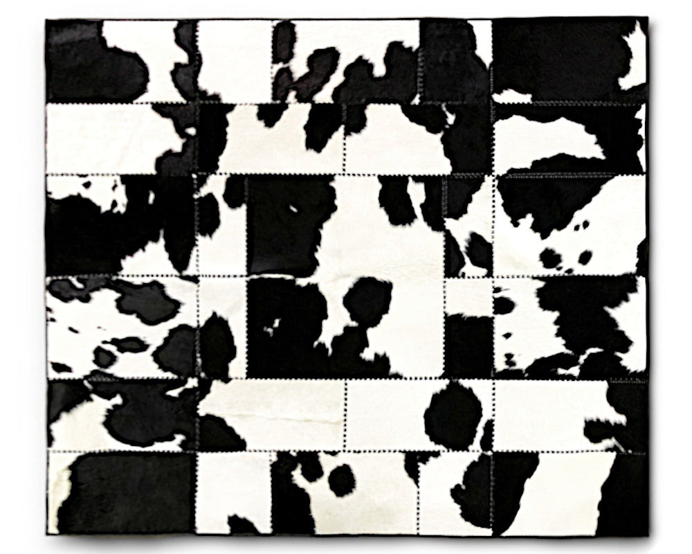 A square patchwork cowhide rug featuring a black and white cow print pattern made of stitched rectangular panels.