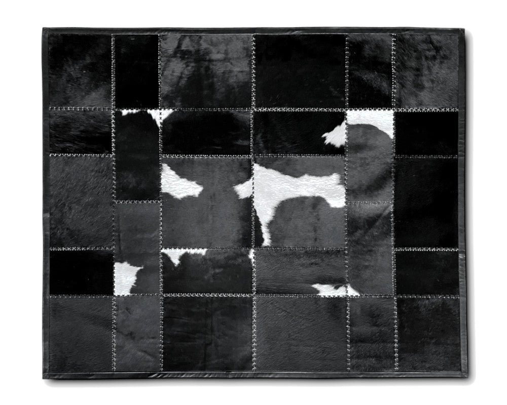 A square patchwork cowhide rug in black and white, featuring stitched sections of different textured hide pieces forming a cow pattern, shown against a plain white background.