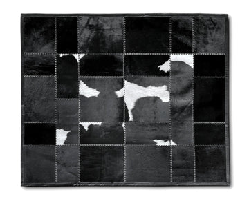 A square patchwork cowhide rug in black and white, featuring stitched sections of different textured hide pieces forming a cow pattern, shown against a plain white background.