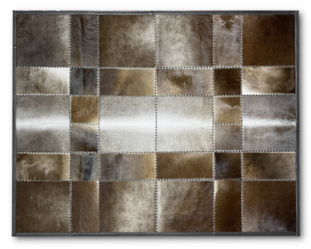 A square patchwork rug featuring a grid of irregular leather or faux-leather panels in earthy brown, beige, gray, and metallic silver tones, separated by white stitching and finished with a dark gray border.