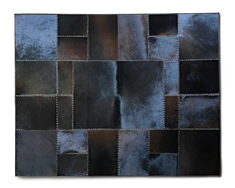 A square patchwork wall hanging or rug featuring rectangular sections of dark brown, black, and blue-gray textured leather or faux leather, stitched together with visible white stitching lines.