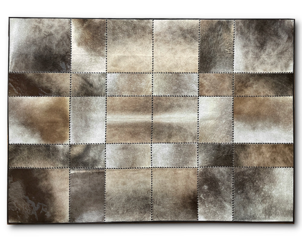 A rectangular patchwork rug made of stitched square panels in mixed brown, beige, gray, and white tones, shown from above on a white background.
