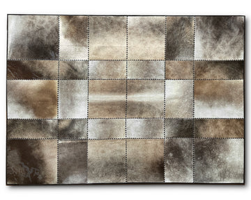 A rectangular patchwork rug made of stitched square panels in mixed brown, beige, gray, and white tones, shown from above on a white background.