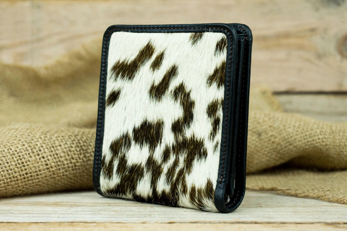 Three-Quarter View: Three-quarter view of a genuine leather cowhide wallet highlighting its unique natural hide pattern and black leather trim.